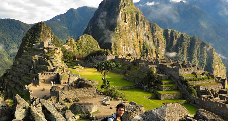 Machu Picchu con turista sentado en primer plano.