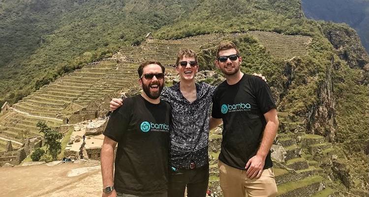 Tres personas posando con las terrazas de Machu Picchu al fondo.