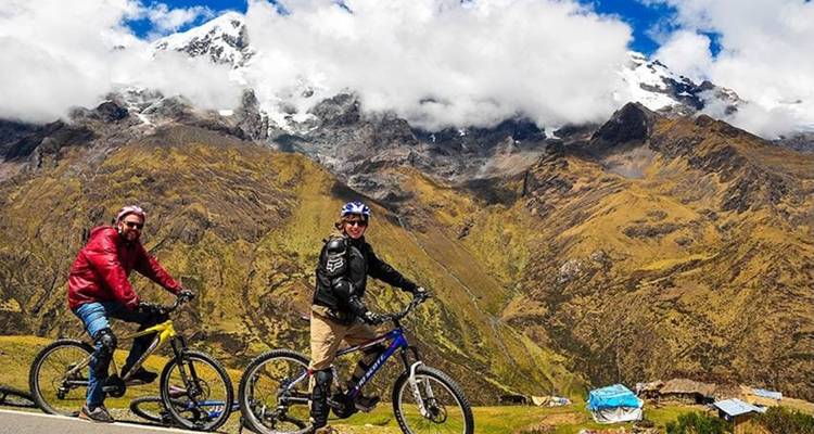 Deux personnes à vélo avec des montagnes en arrière-plan.