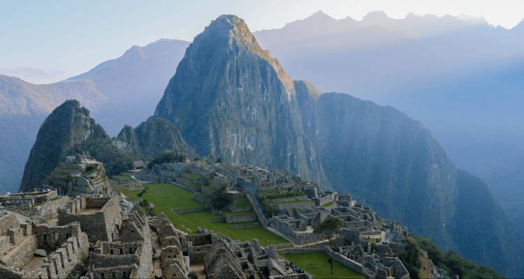 Icónica panorámica de las ruinas de Machu Picchu encaramadas bajo el imponente pico Huayna Picchu bañado por la suave luz matutina.