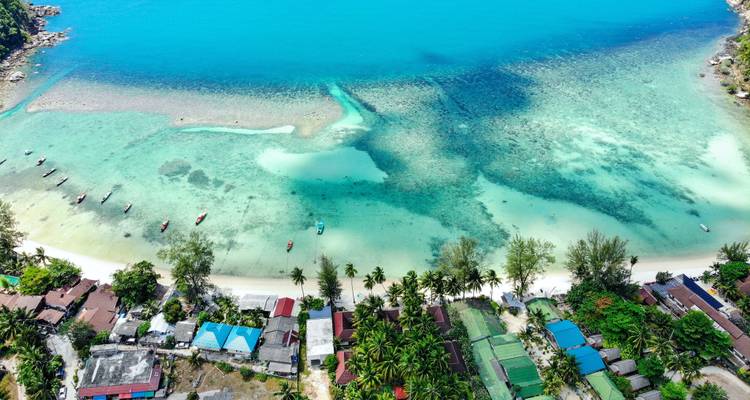 Vue aérienne d'une plage tropicale aux eaux turquoise.