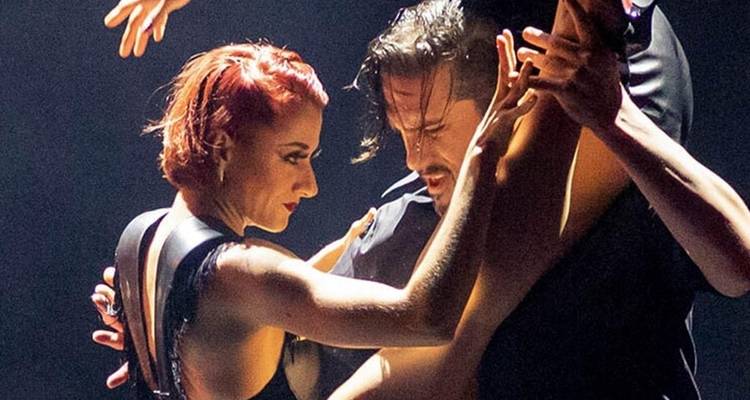 Gros plan dramatique d'un couple de tango exécutant une danse intense sous l'éclairage de la scène.