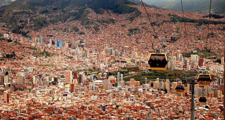 Vue panoramique de La Paz s'étendant à travers une vallée avec des télécabines jaunes glissant au-dessus du paysage urbain.