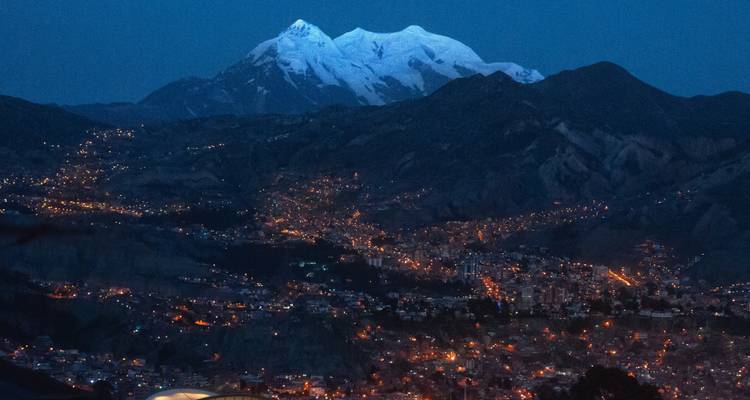 Vue nocturne des lumières de la ville de La Paz s'étendant sous le Mont Illimani aux pics enneigés.