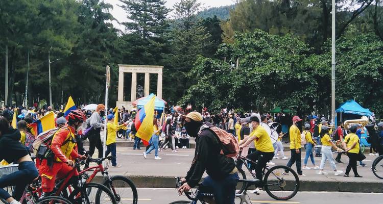 Foule de cyclistes et de piétons participant à une manifestation de rue dynamique avec des drapeaux et de la musique.