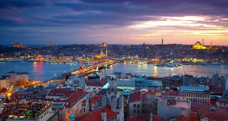 Un paysage urbain au crépuscule avec des bâtiments illuminés et un plan d'eau.