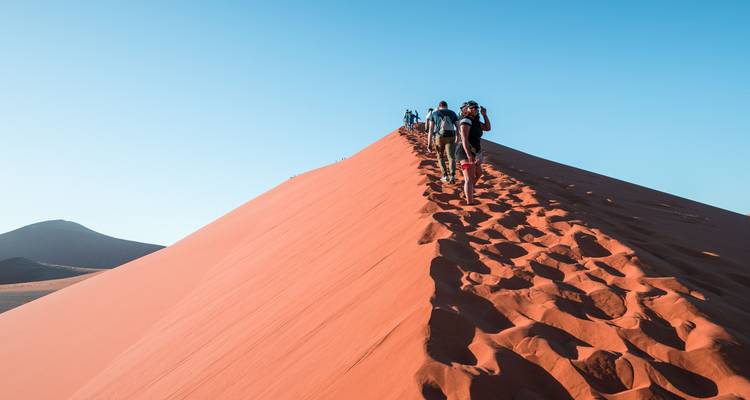 Personas caminando por la cima de una gran duna de arena.