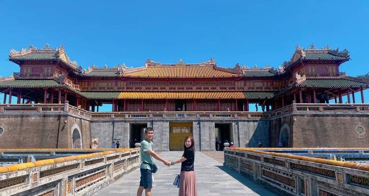 Pareja tomada de la mano frente a una estructura asiática tradicional.