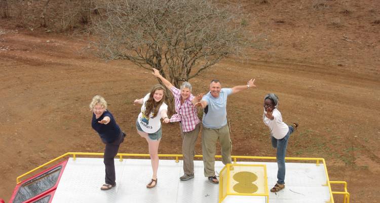 Group of people posing on a vehicle roof.