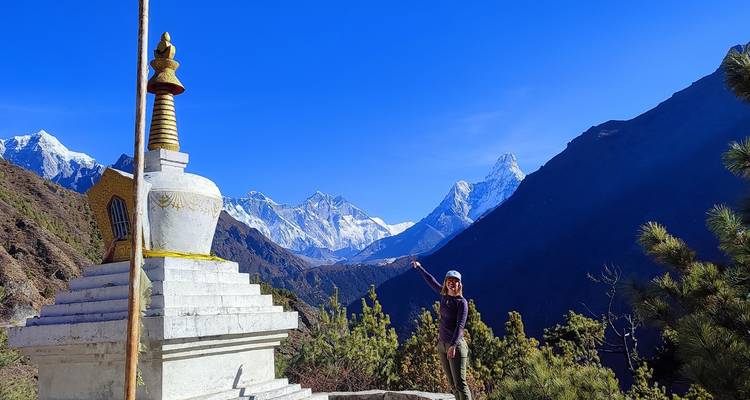 Una persona posando frente a una estupa con las montañas del Himalaya al fondo.