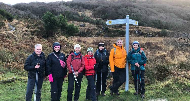 Un groupe de randonneurs posant à côté d'une borne, sur fond de collines.