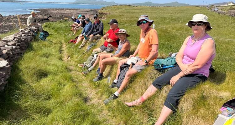 Un groupe de randonneurs se reposant sur l'herbe près d'une côte rocheuse.
