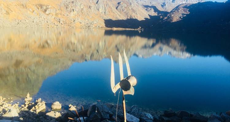 Reflejo de montañas en un lago tranquilo con un tridente en primer plano.