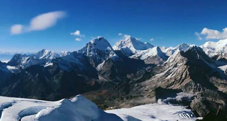 Une vue panoramique d'une chaîne de montagnes enneigées sous un ciel bleu.