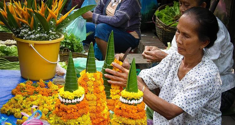 Mujer elaborando decoraciones florales en un puesto de mercado.