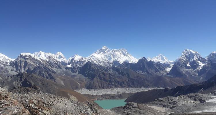 Majestuosa cordillera con picos cubiertos de nieve sobre un lago turquesa.