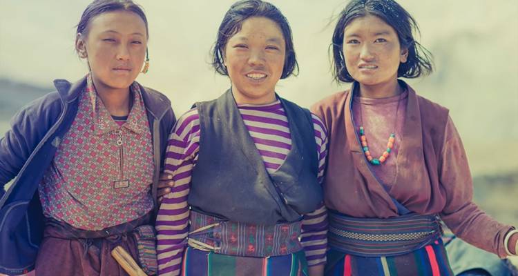Trois personnes vêtues de tenues traditionnelles souriant à la caméra.