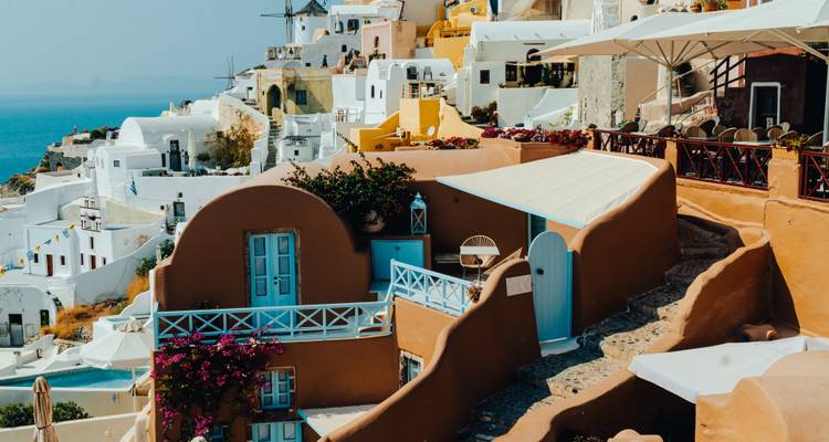 Kleurrijke Cycladeische huizen en terrassen met blauwe deuren en bougainville met uitzicht op de zee in Santorini