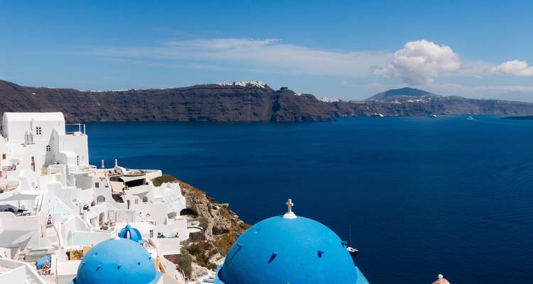 Acantilado de Santorini con iglesias de cúpulas azules y vista al mar.