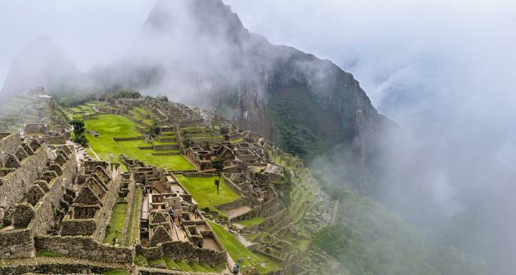 Vue large du Machu Picchu avec de la brume recouvrant une partie des montagnes.