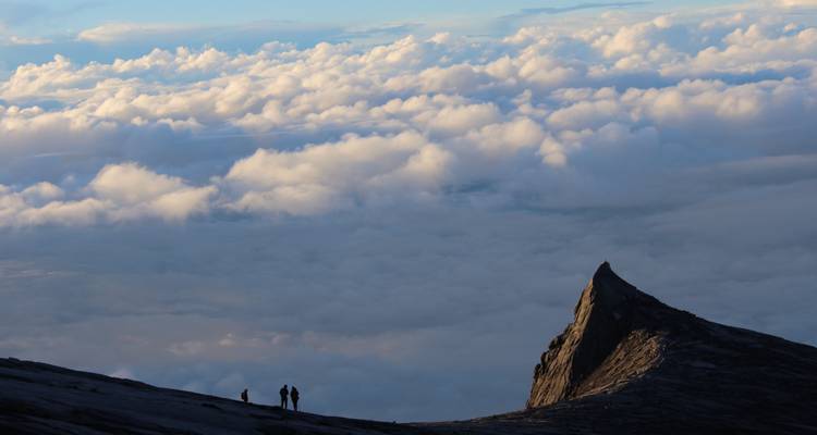 Les petits alpinistes se tiennent sur le plateau sommital en granit du Mont Kinabalu au-dessus d'une mer de nuages
