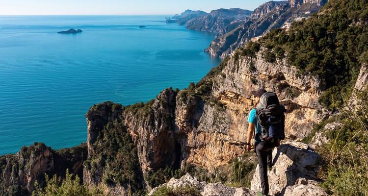 Un excursionista disfrutando de una vista impresionante de una costa con acantilados y océano.