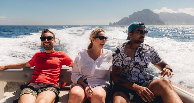 Personas disfrutando de un paseo en barco con mar y acantilados.