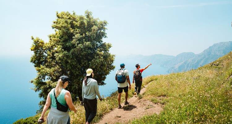 Grupo de excursionistas caminando por un sendero panorámico con vista a la costa.