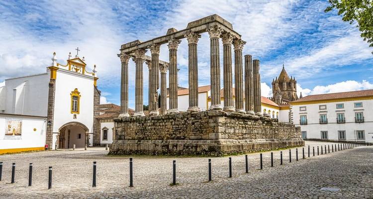 L'ancien Temple romain d'Évora se dressant fièrement sur une place pavée lumineuse sous un ciel bleu.