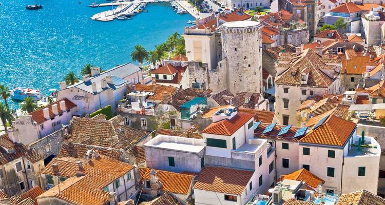Dachziegelmuster des historischen Zentrums von Split mit azurblauen Adria-Gewässern und palmengesäumter Promenade.