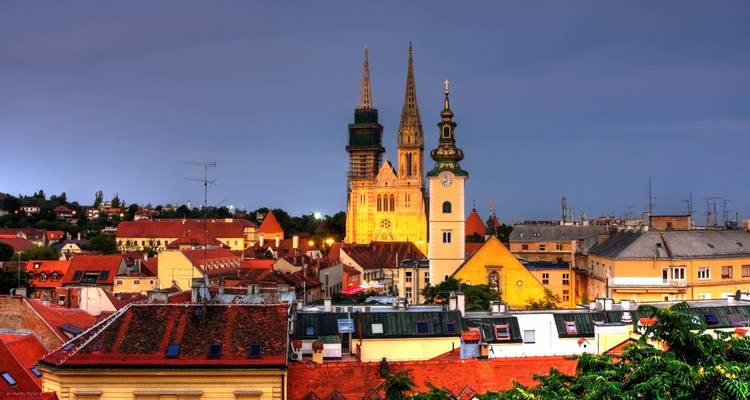 Panorama nocturna de Zagreb con las dos agujas de la catedral iluminadas sobre los tejados rojos.