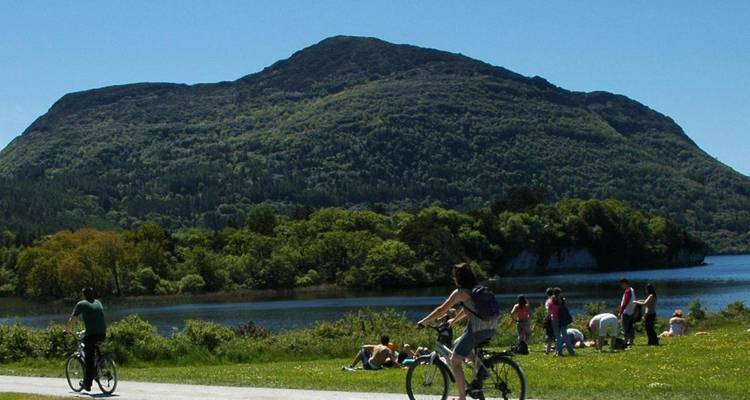Mensen die fietsen en ontspannen bij een meer met uitzicht op de bergen.