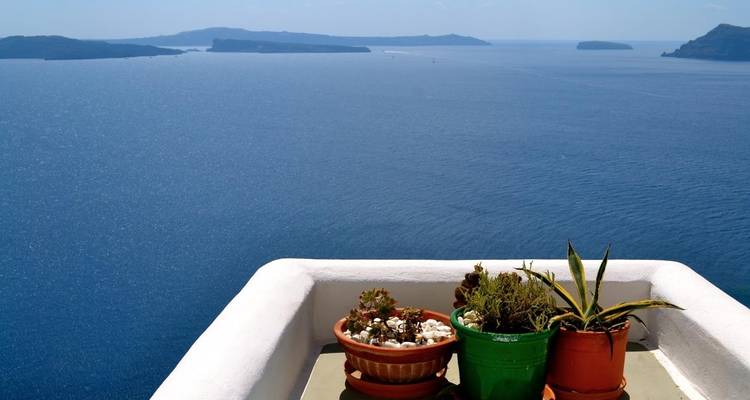 Potplanten op een richel met uitzicht op de zee met eilanden in zicht.