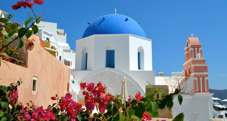 Kerk met blauwe koepel, roze klokkentoren en levendige bloemen.