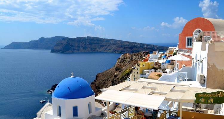 Witte en pastelkleurige gebouwen langs een klif met blauwe zee.