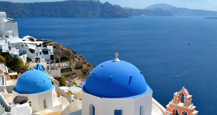 Kerken met blauwe koepels en witte gebouwen op een klif met uitzicht op zee.