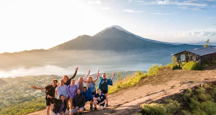 Groep mensen die poseren met een schilderachtig uitzicht op bergen en een meer.