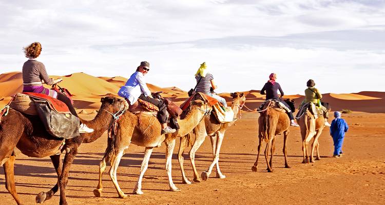 A group of people riding camels through the desert.