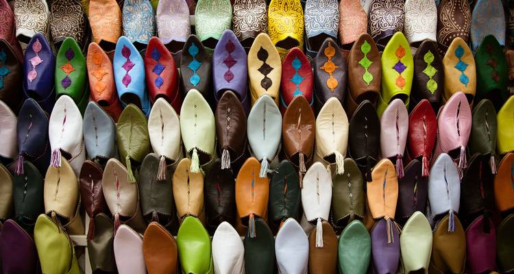 Rows of brightly coloured Moroccan leather slippers are neatly stacked in a souk display.