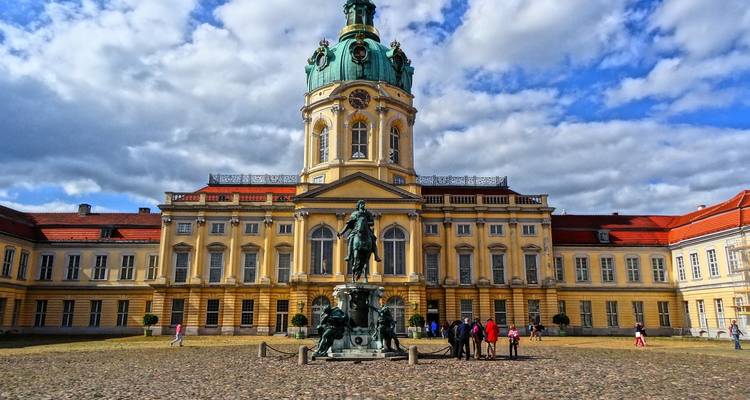 Binnenplein van het Paleis Charlottenburg met standbeeld en gele barokke gevel onder een heldere hemel.