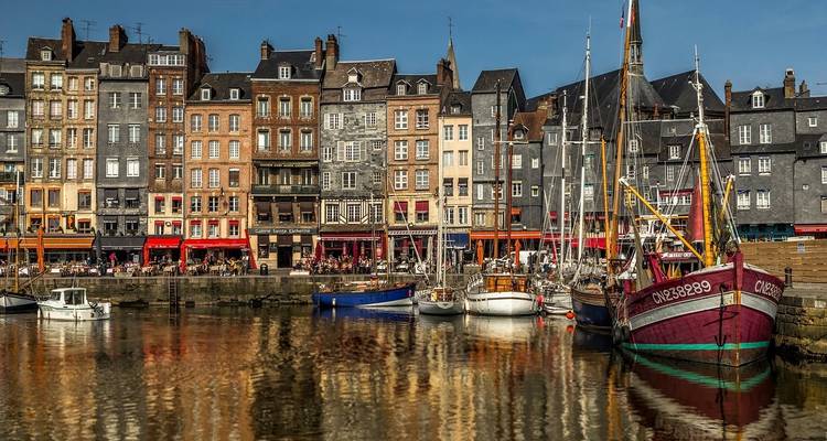 Vue panoramique sur le front de mer avec des bâtiments historiques colorés et des bateaux.