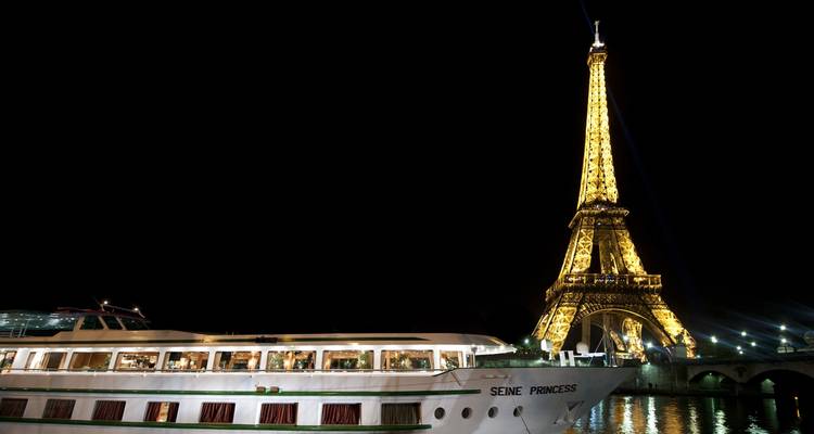 Bateau de croisière Seine Princess avec la Tour Eiffel illuminée la nuit.