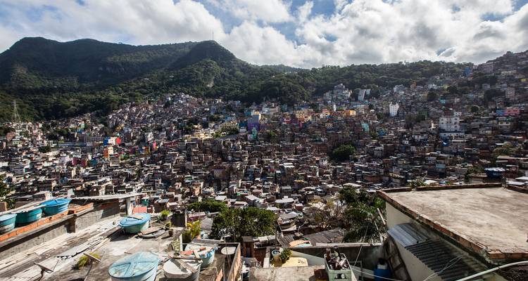 Panoramablick über eine ausgedehnte Rio-Favela vor dem Hintergrund üppig grüner Hügel.