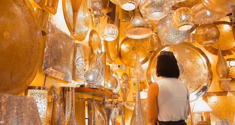 Vista interior de una tienda con una mujer mirando lámparas de metal intrincadas.