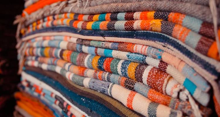 Primer plano de alfombras o telas tejidas coloridas apiladas.