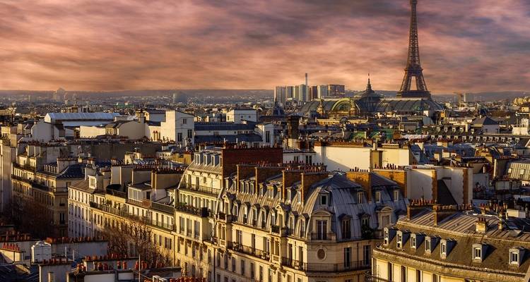 Vue panoramique des toits de Paris avec la Tour Eiffel au coucher du soleil.
