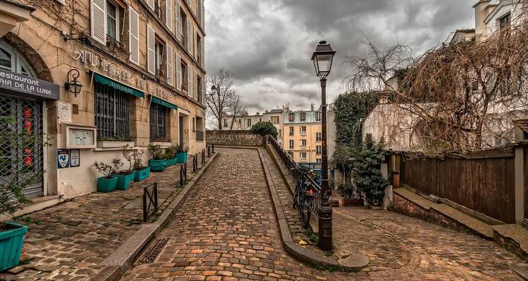 Charmante rue pavée dans une ville historique avec un ciel nuageux.