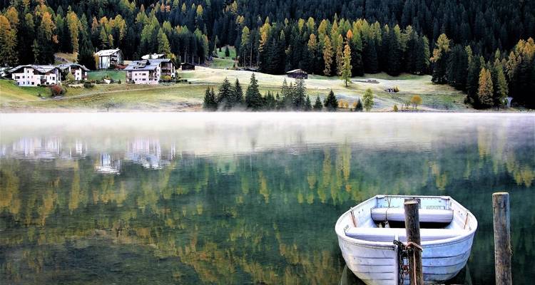 Lac calme avec un bateau et des arbres aux couleurs d'automne.