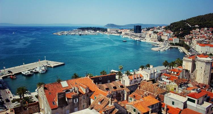 Une vue panoramique d'une ville côtière avec des toits de tuiles rouges et une marina.