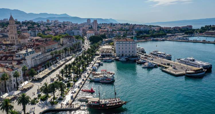 Vista aérea del frente marítimo histórico de Split, paseo marítimo bordeado de palmeras y puerto bullicioso
